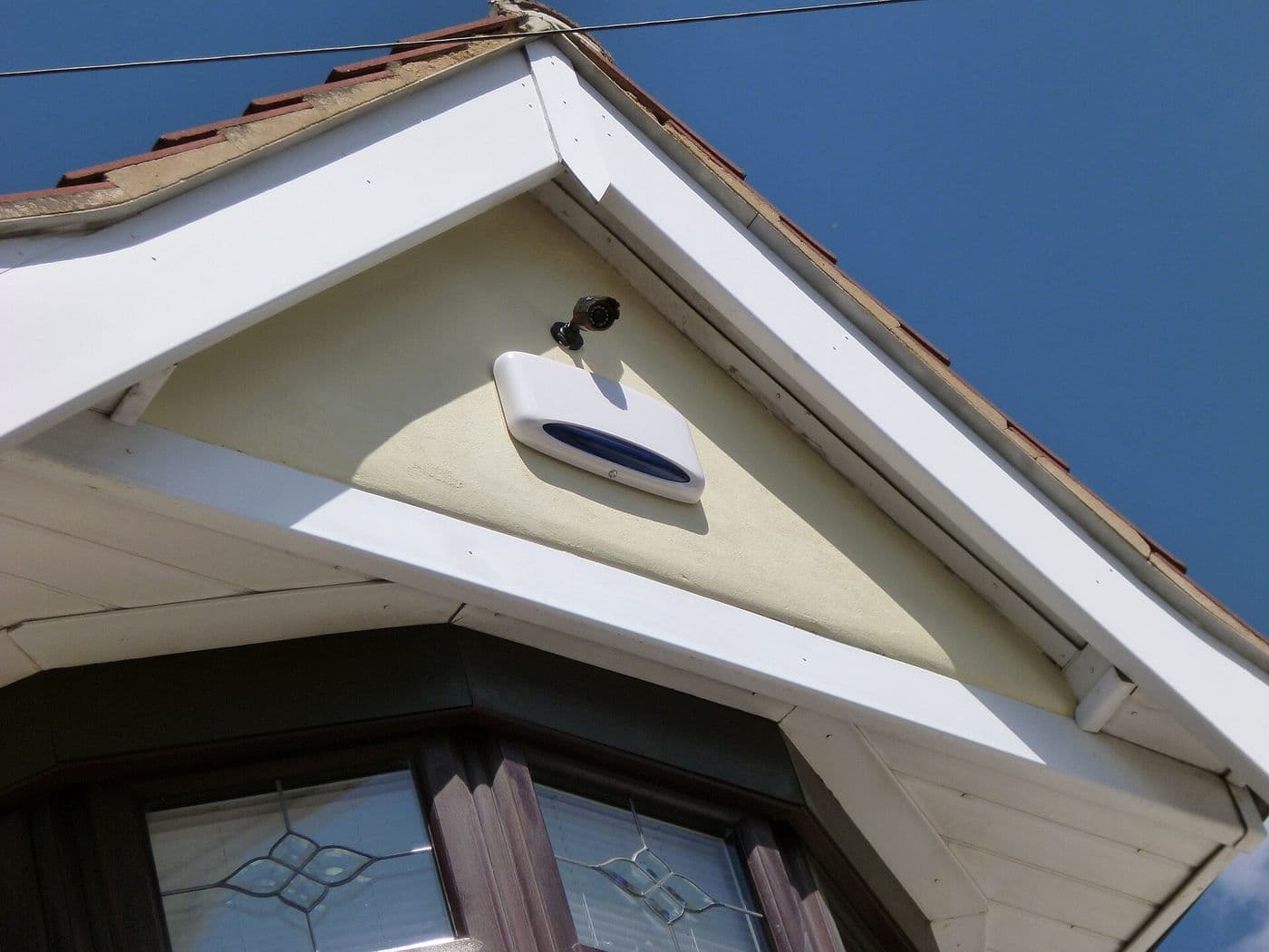 Alarm bell box mounted on the front wall of a home.