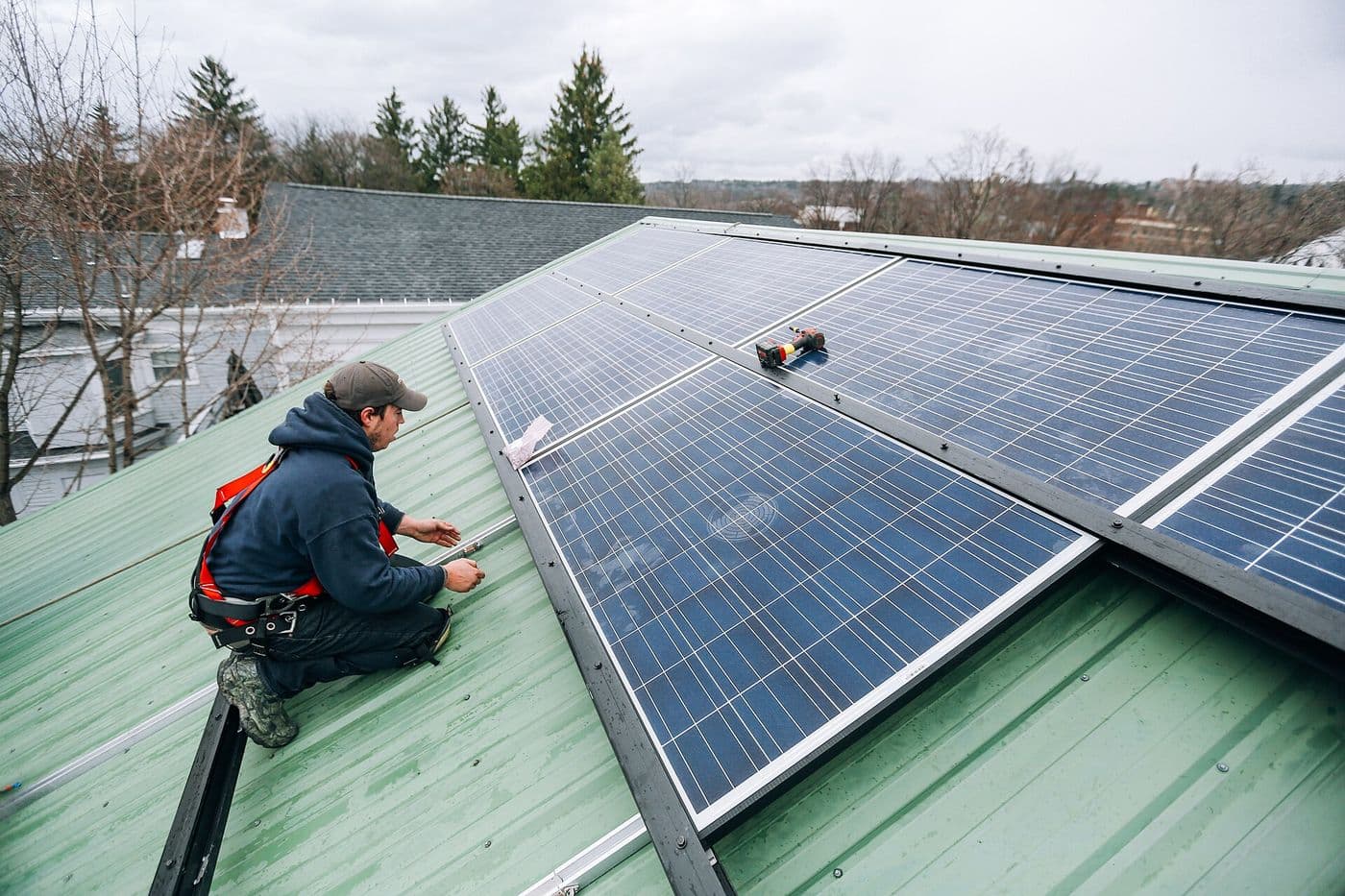 Technicians installing solar panels that charge a home backup system.